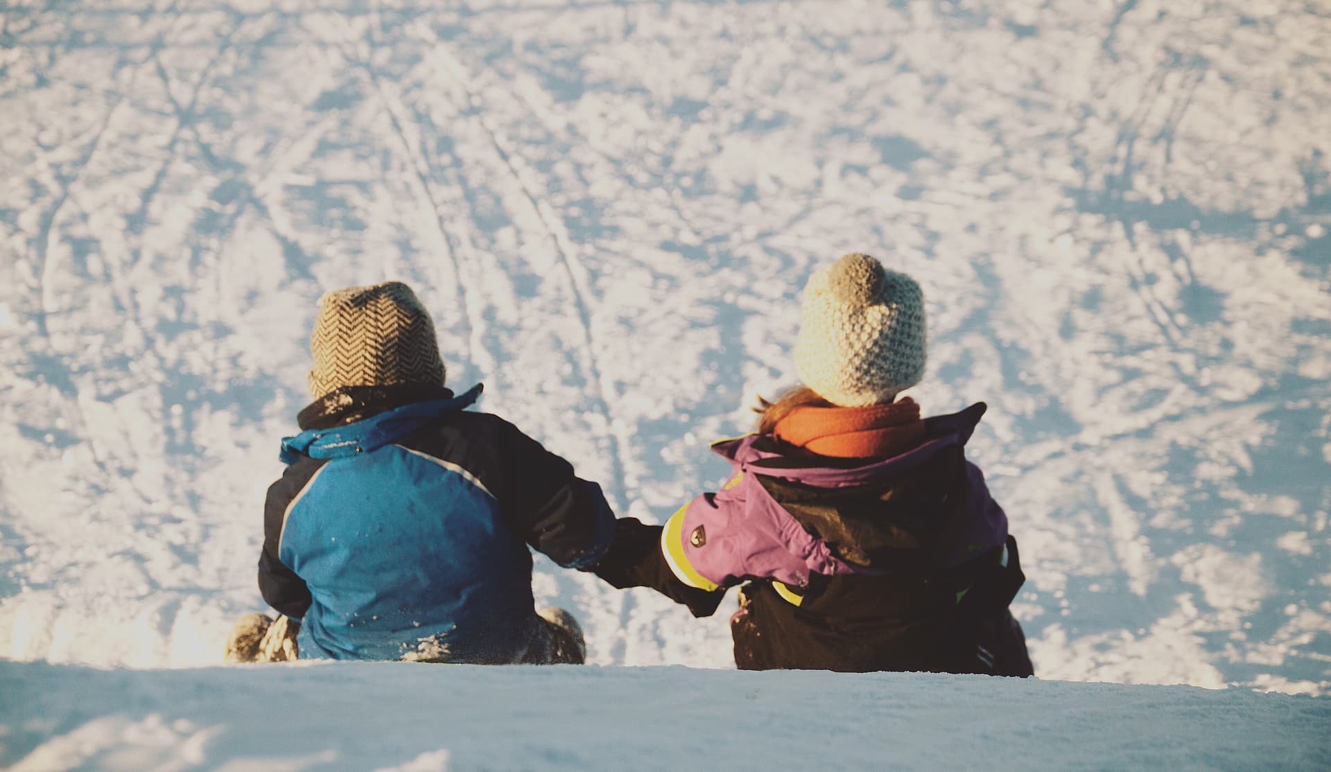 Two children holding hands sitting on a hill