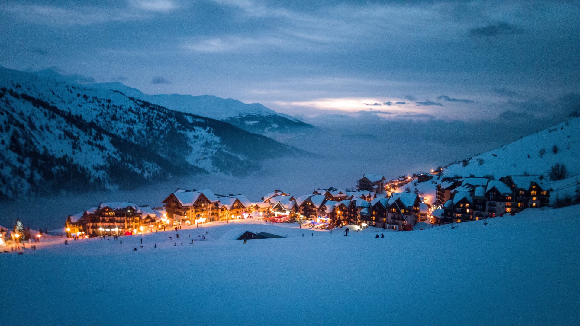 a snowy town by sunset with the lights on at Valmeinier Tourism Board