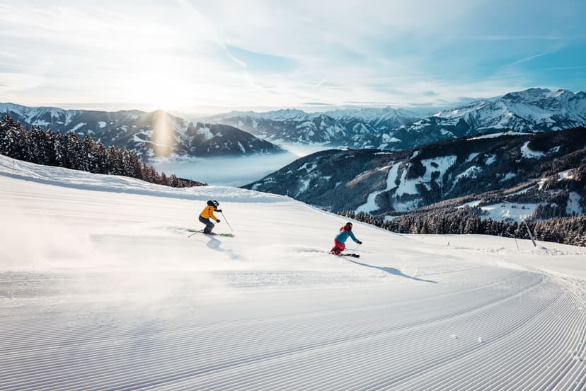 skiers skiing down freshly groomed piste at sunset in Kaprun